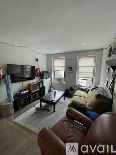 A living room with a brown leather couch and a television.