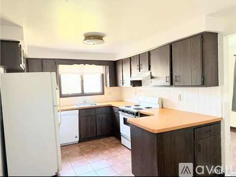 A kitchen with a white refrigerator, wooden cabinets, and a tiled floor.
