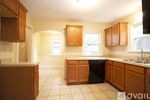 A kitchen with brown cabinets and a black trash can.