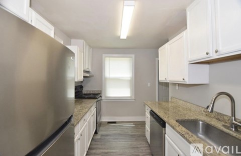 A kitchen with a stainless steel refrigerator and white cabinets.