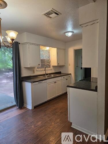 A kitchen with white cabinets and a black countertop.