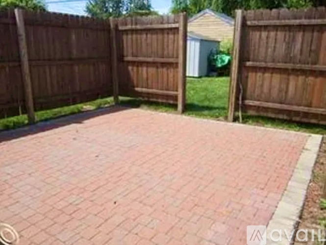A backyard with a brick patio and a wooden fence.