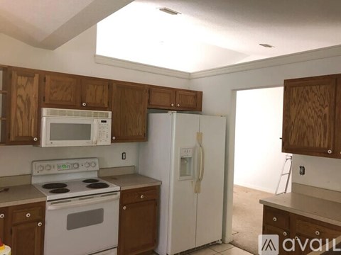 A kitchen with a white refrigerator and wooden cabinets.