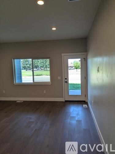 A room with a door and a window overlooking a green area.