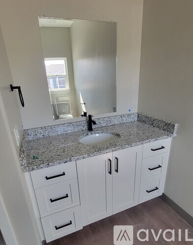 A bathroom with a granite countertop and white cabinets.
