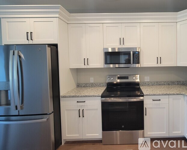 A kitchen with white cabinets and a stainless steel refrigerator.