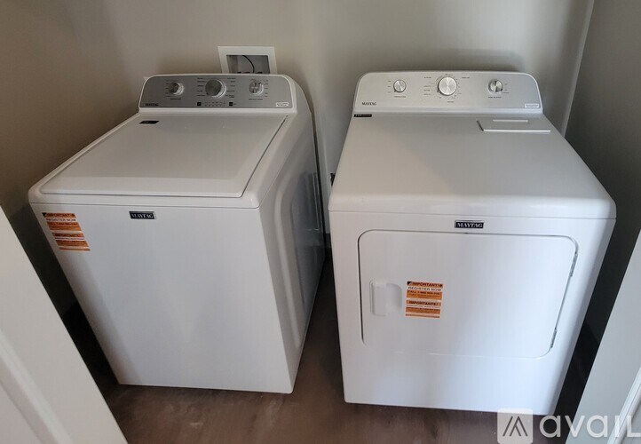 Two white front loading washing machines in a laundry room.