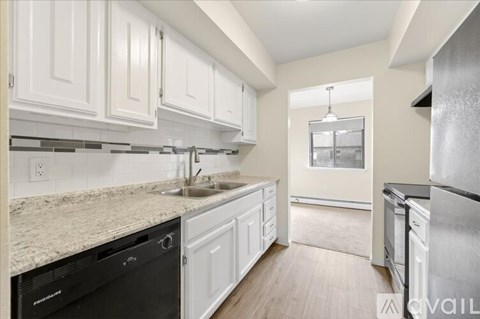 A kitchen with white cabinets and a black dishwasher.