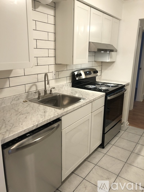 A kitchen with a stove, sink, and cabinets.