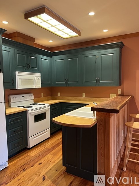 A kitchen with dark green cabinets and a white stove top oven.