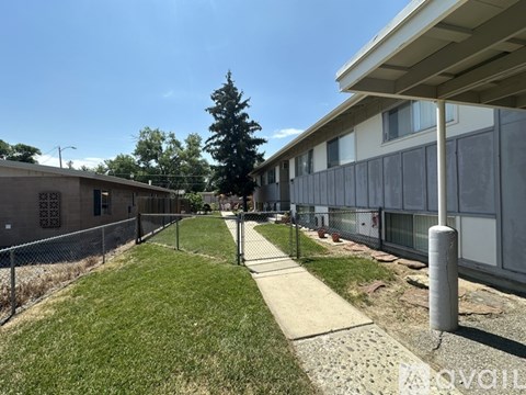 A long concrete walkway leads to a building with a metal fence on one side.