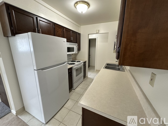 A kitchen with a white refrigerator and brown cabinets.