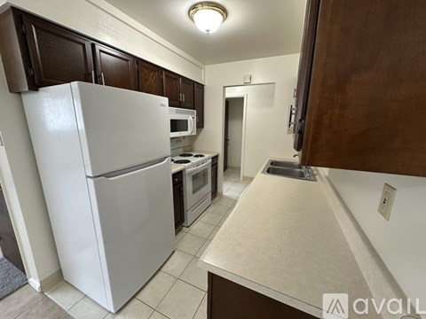 A kitchen with a white refrigerator and brown cabinets.