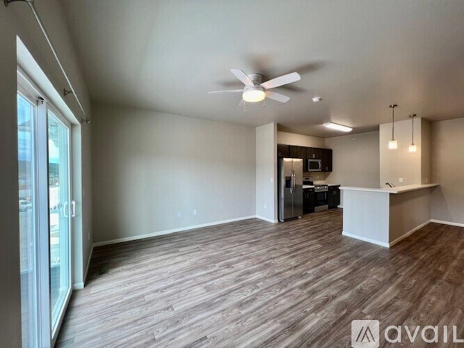 A spacious room with a ceiling fan and a kitchenette in the background.