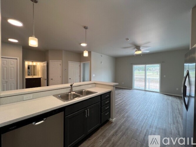 A spacious kitchen with a sink, cabinets, and a ceiling fan.