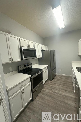 A kitchen with white cabinets and a black microwave.