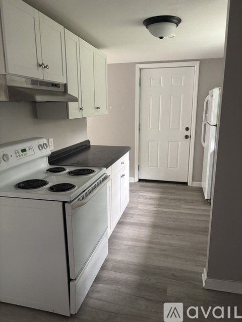 A white stove top oven with four burners and a white refrigerator in a kitchen.