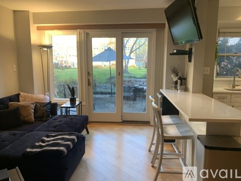 A living room with a couch, a chair, and a television mounted on the wall.