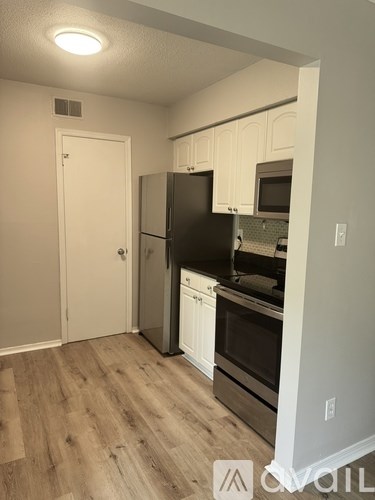A kitchen with black appliances and white cabinets.