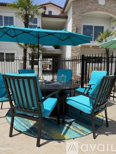 A patio table with four chairs and a blue umbrella.