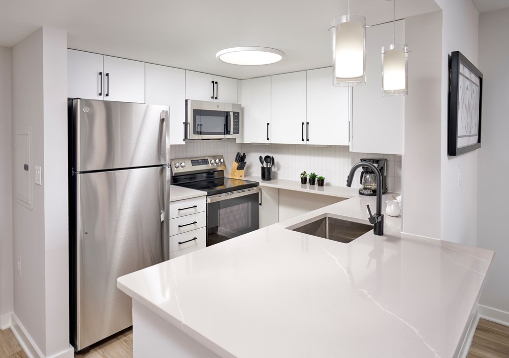 A modern kitchen with a white countertop and stainless steel appliances.