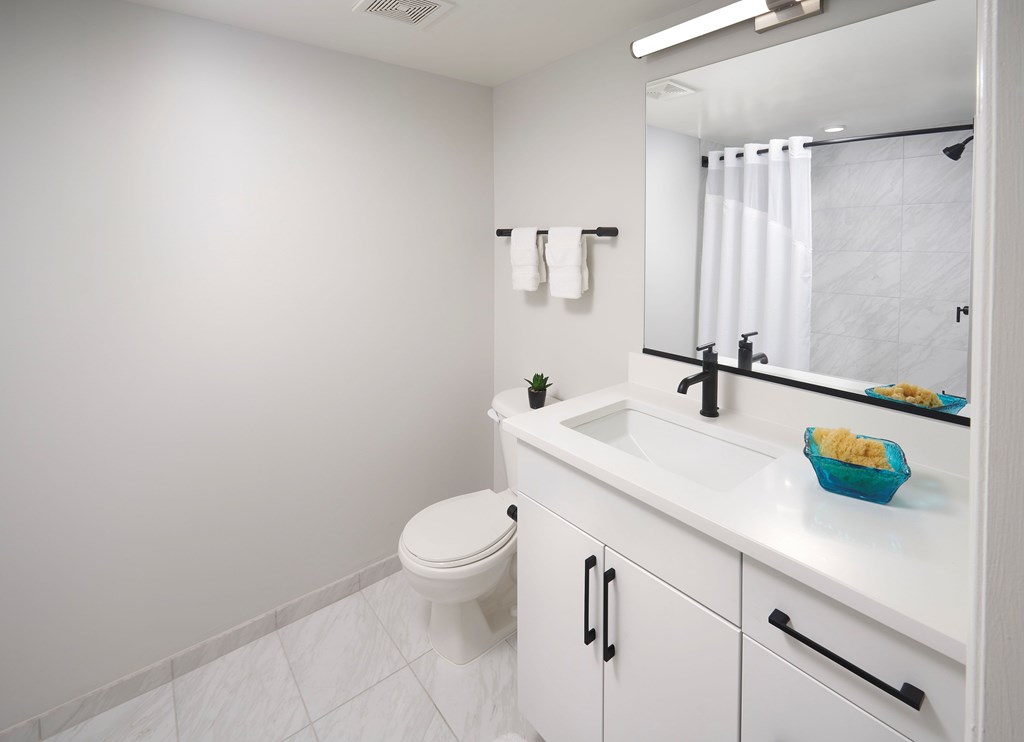 A white bathroom with a toilet, sink, and mirror.