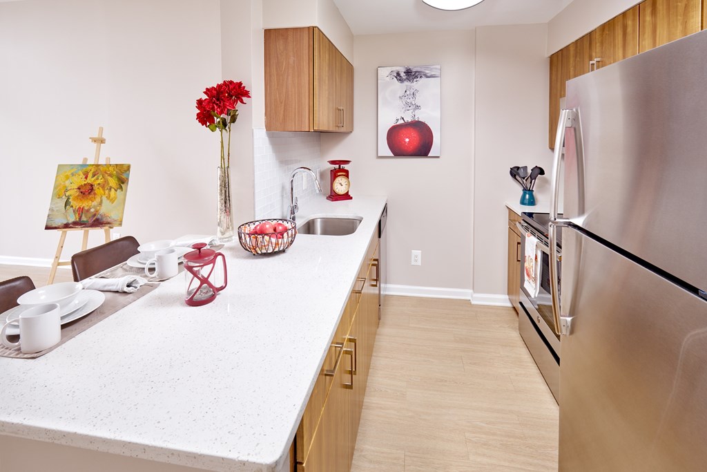 A kitchen with a white counter top and a stainless steel refrigerator.