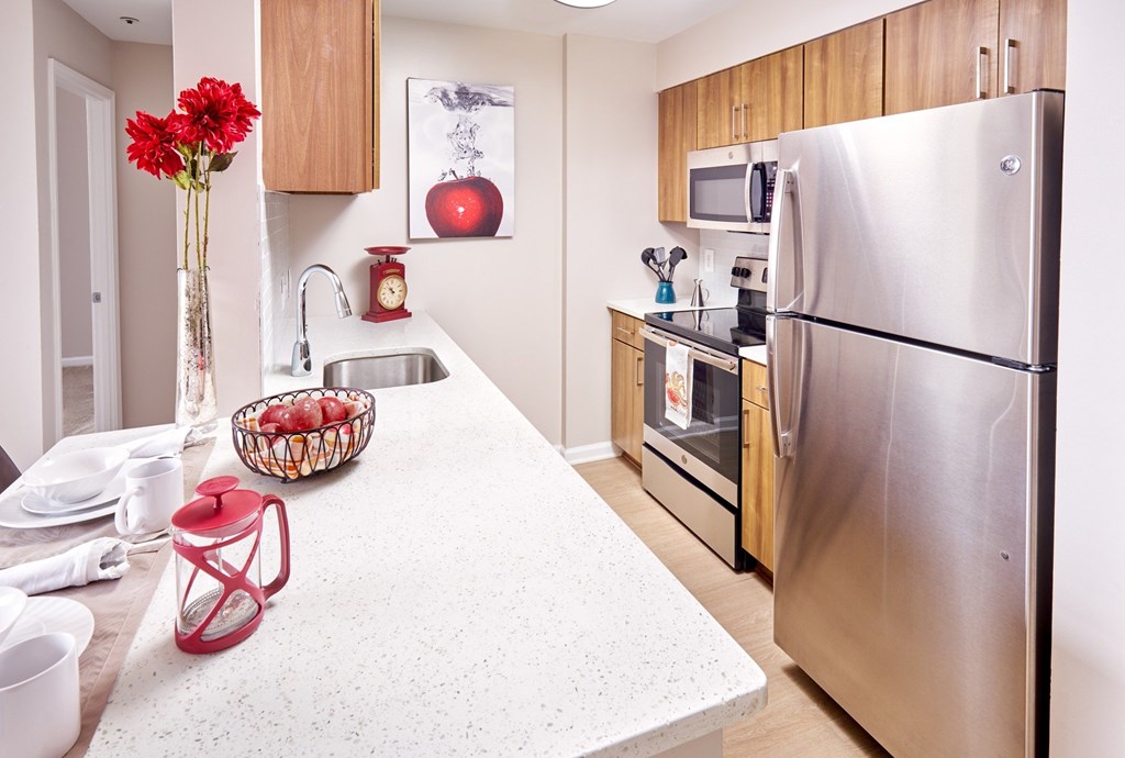 A kitchen with a stainless steel refrigerator and wooden cabinets.
