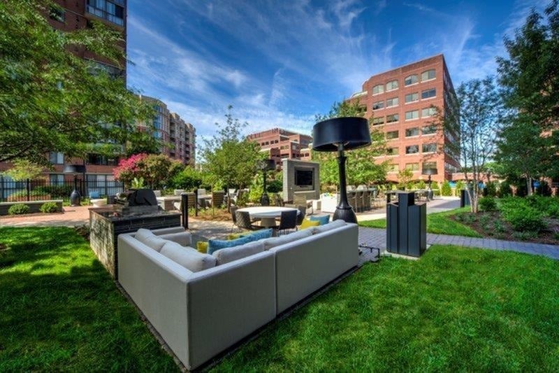 A modern outdoor seating area with a large speaker on a stand.