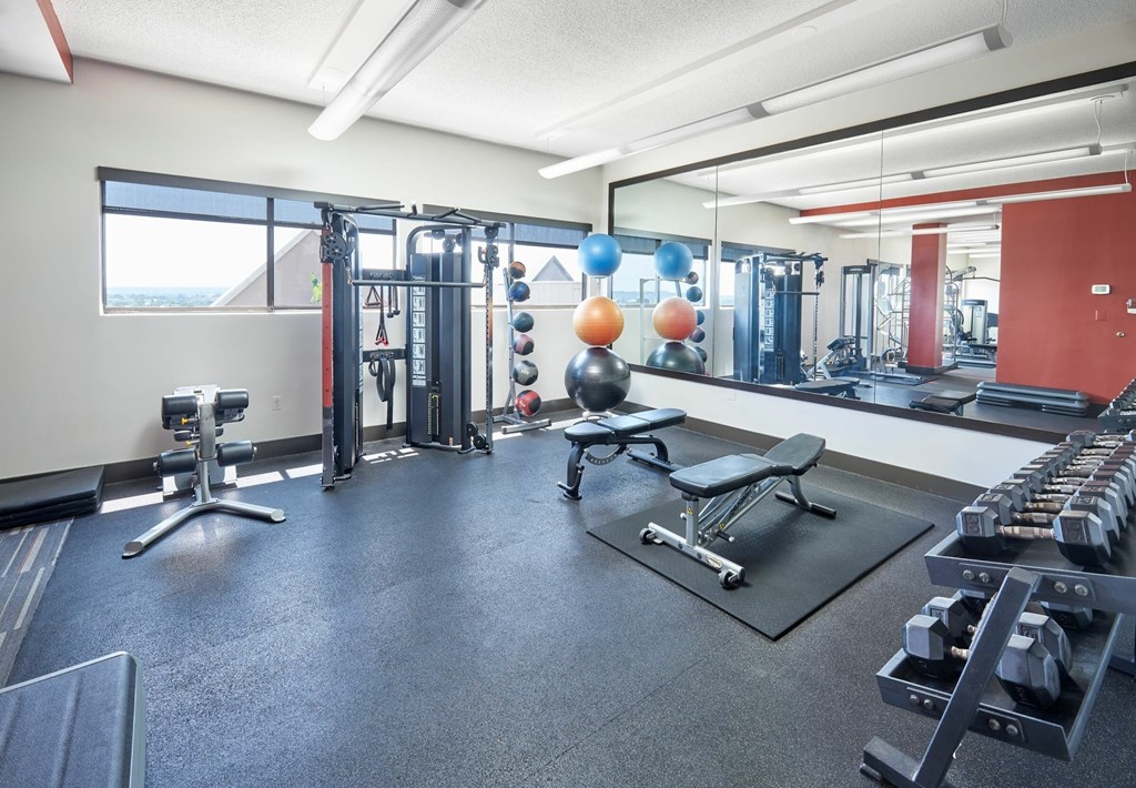 A gym with a variety of equipment including dumbbells, weight machines, and benches.