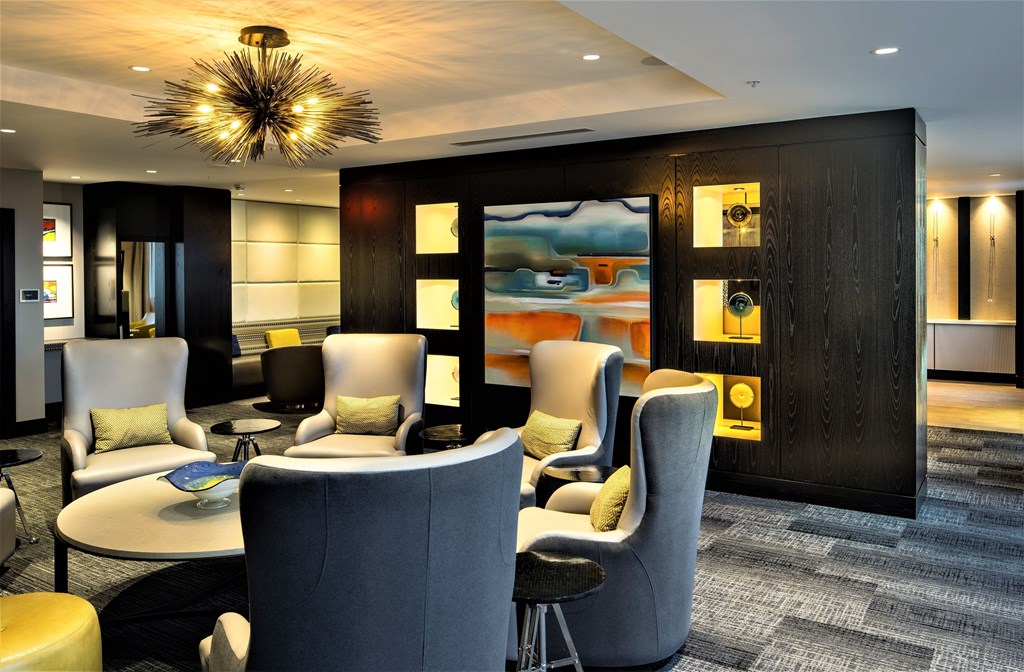 A modern lounge area with grey and white chairs and a large abstract painting on the wall.