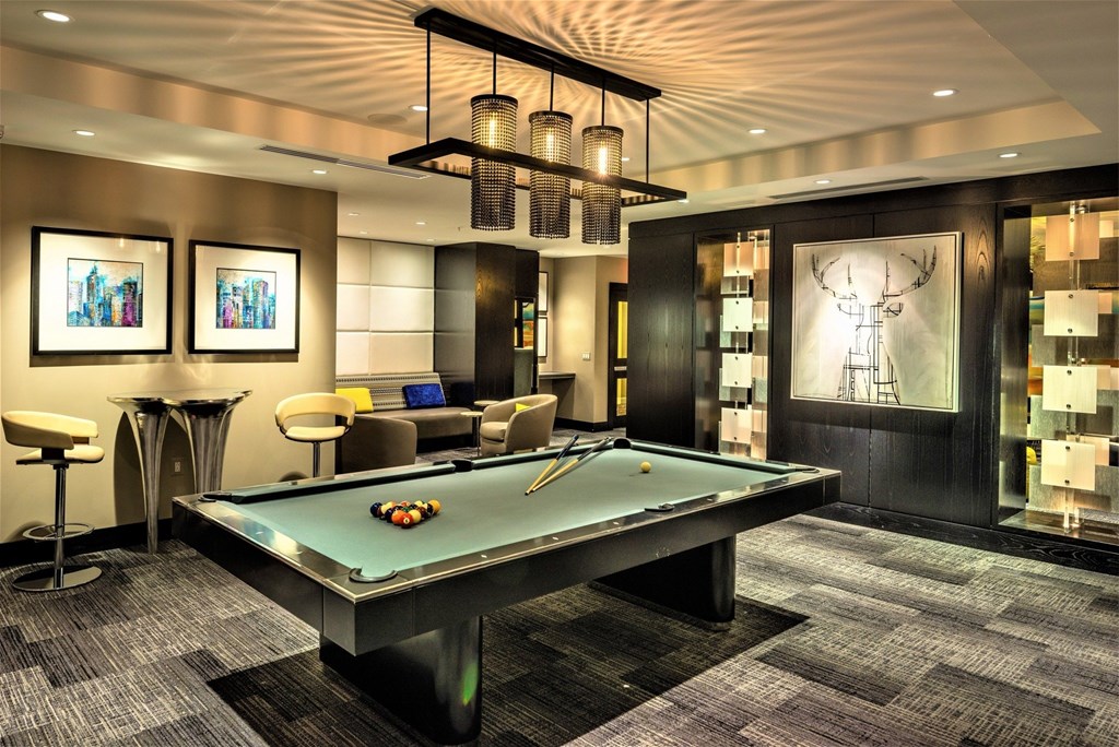 A pool table in a room with a bar and a painting on the wall.