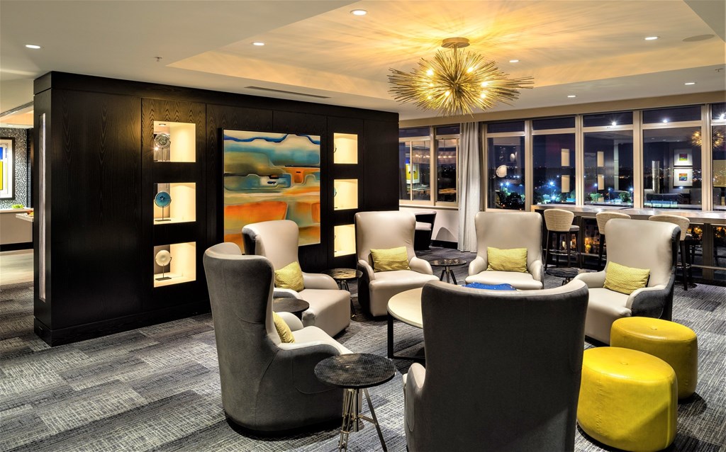 A modern lounge area with grey and yellow chairs and a large painting on the wall.