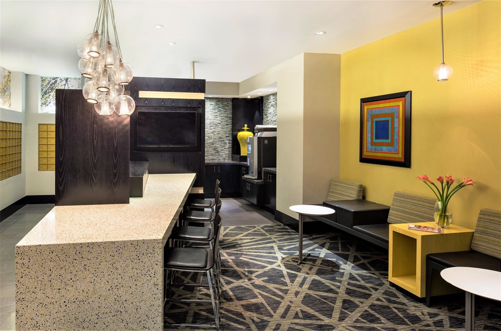 A yellow wall with a picture and a vase of flowers on a table.