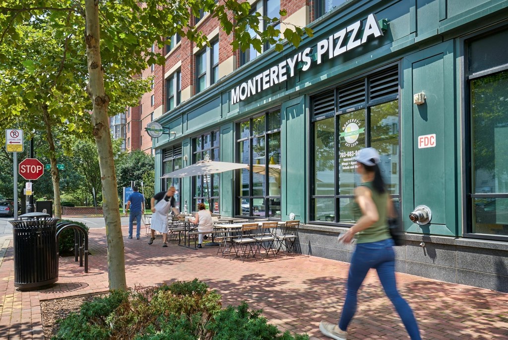 A woman is walking past Monterey's Pizza.