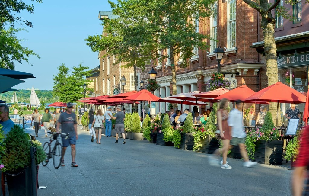A street scene with people walking and biking, and red umbrellas.