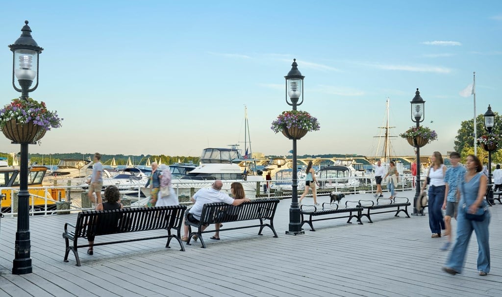 A group of people are sitting on benches on a wooden deck.