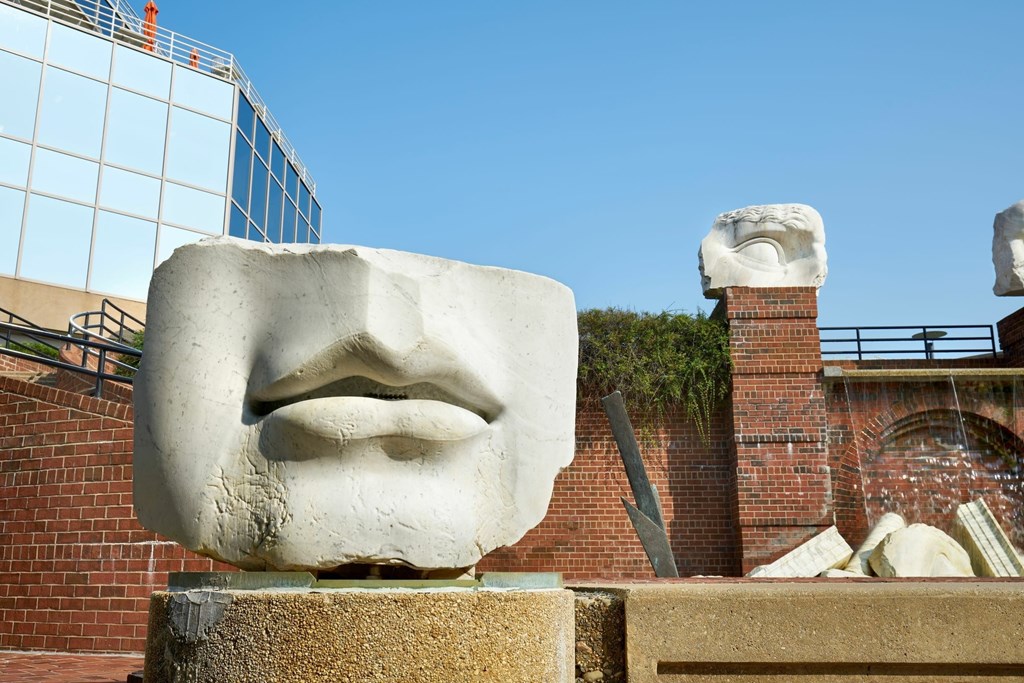A sculpture of a face is displayed in front of a brick wall.