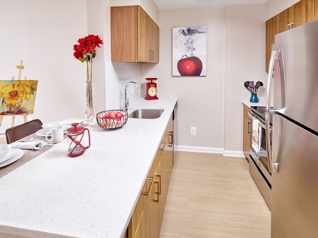 A kitchen with a white counter top and a stainless steel refrigerator.