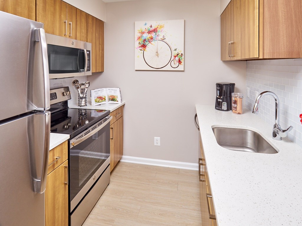 A kitchen with a refrigerator, oven, microwave, sink and cabinets.