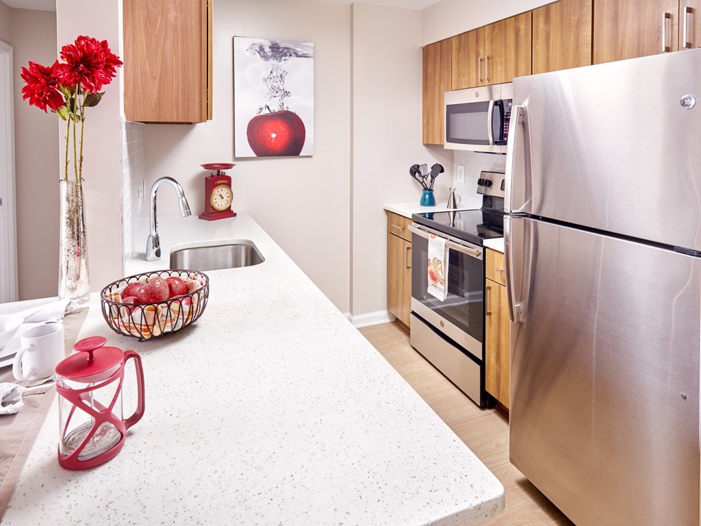 A kitchen with a stainless steel refrigerator and wooden cabinets.