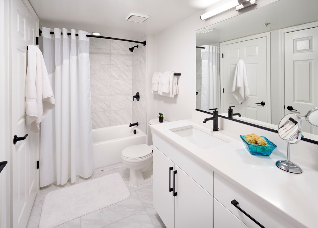 A white bathroom with a white toilet, sink, and shower.