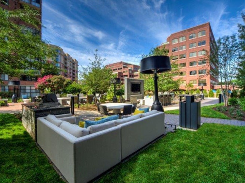 A modern outdoor seating area with a large grey sofa and a black lamp post.