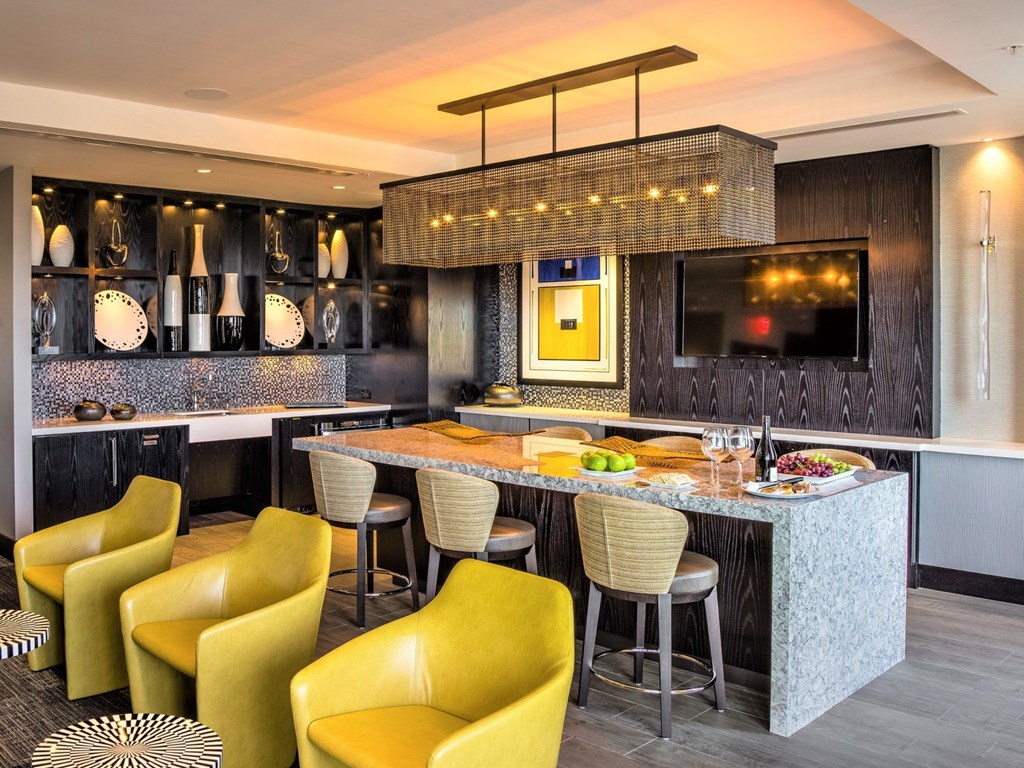 A modern kitchen with a bar area and yellow chairs.