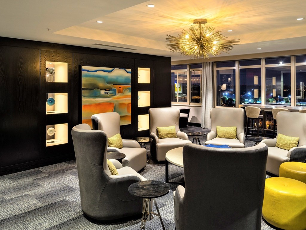 A modern lounge area with grey and yellow chairs and a large painting on the wall.