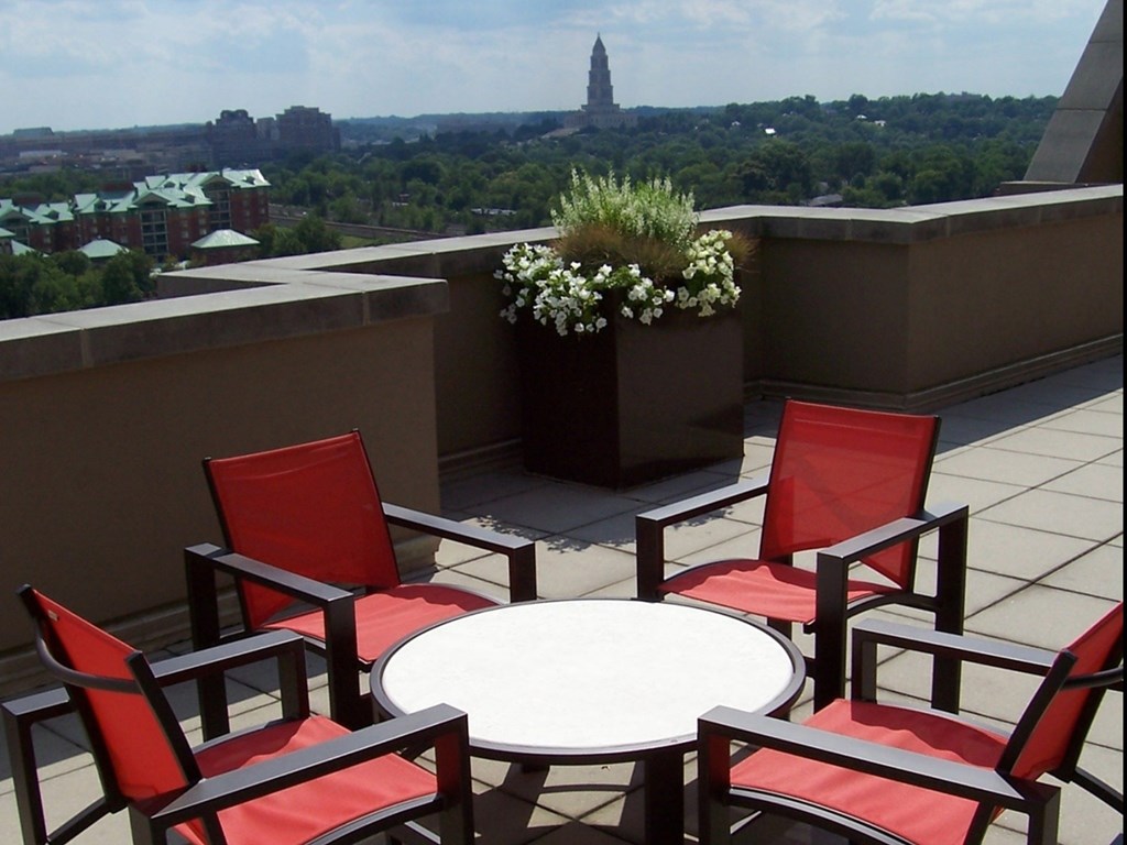 A table surrounded by chairs on a balcony with a view of a city.
