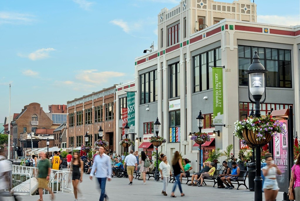 A busy street scene with people walking and sitting on benches.