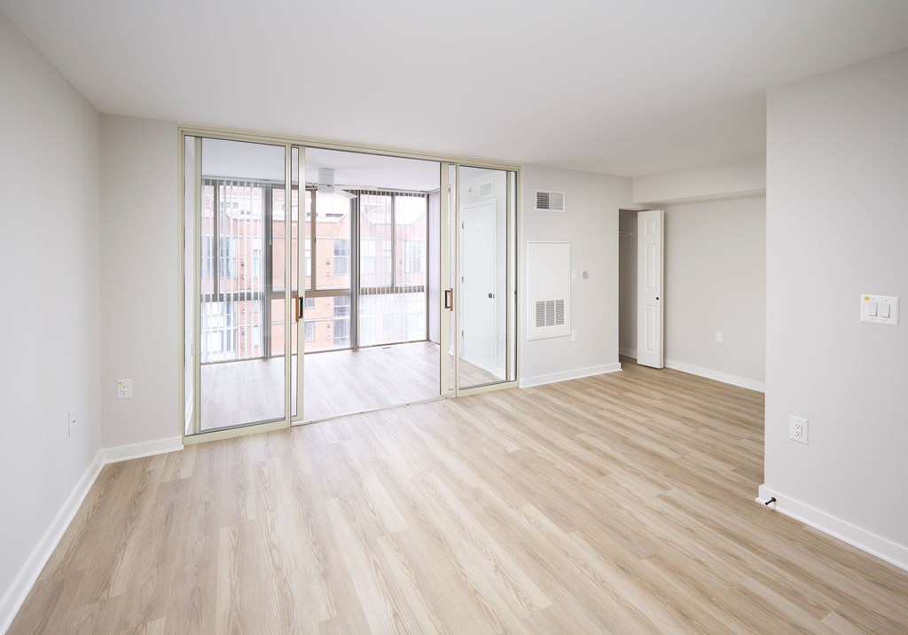 A room with a sliding glass door and wooden flooring.