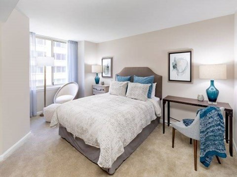 A bedroom with a large bed and a chair by the window.