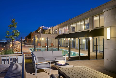 A patio with a couch, table and a pool.
